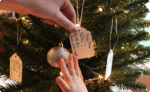 Person putting a tag on a Christmas tree that says girl, age 8